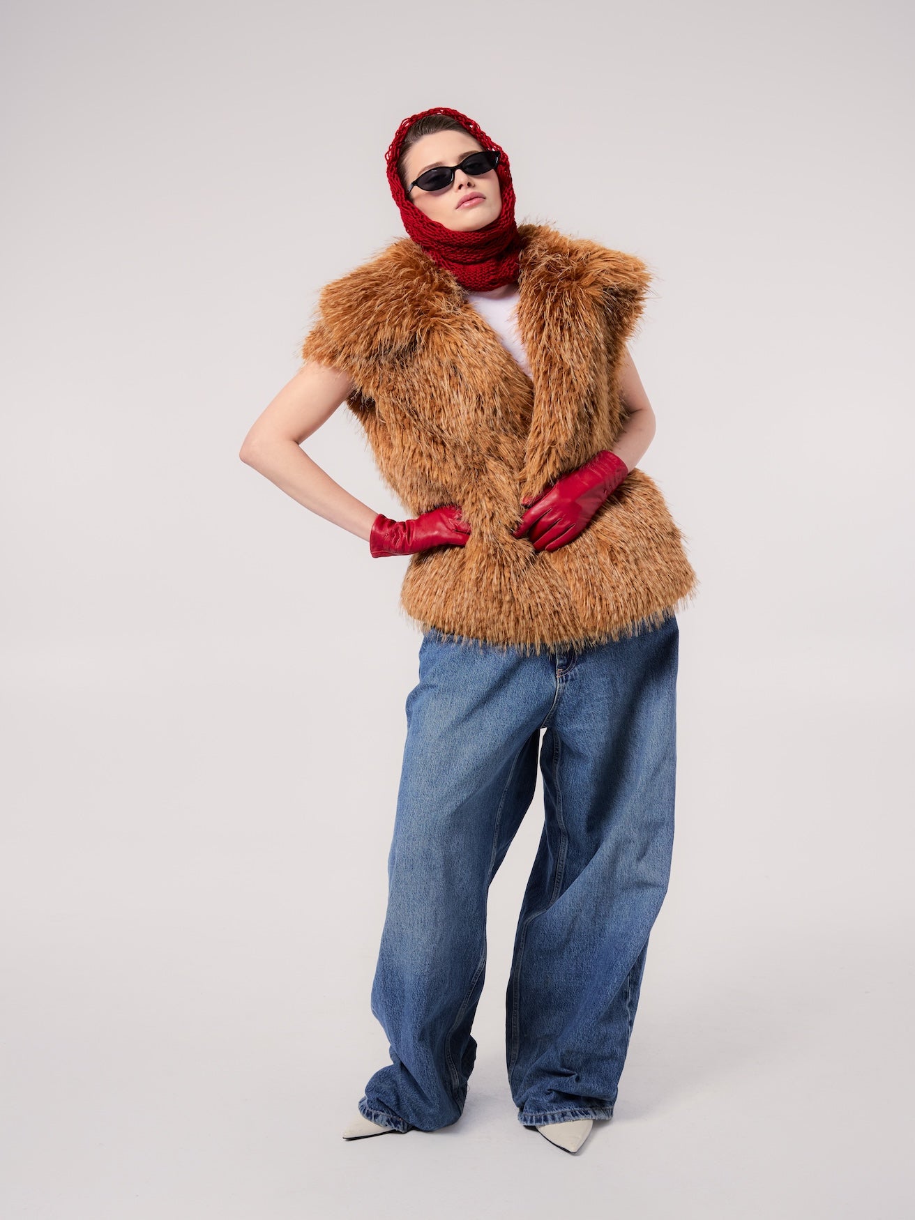 MIA vest in Butterscotch — model wearing a vegan faux fur vest with a long shaggy texture, styled with oversized denim, red leather gloves, a knit hood, and slim sunglasses for a bold editorial look.