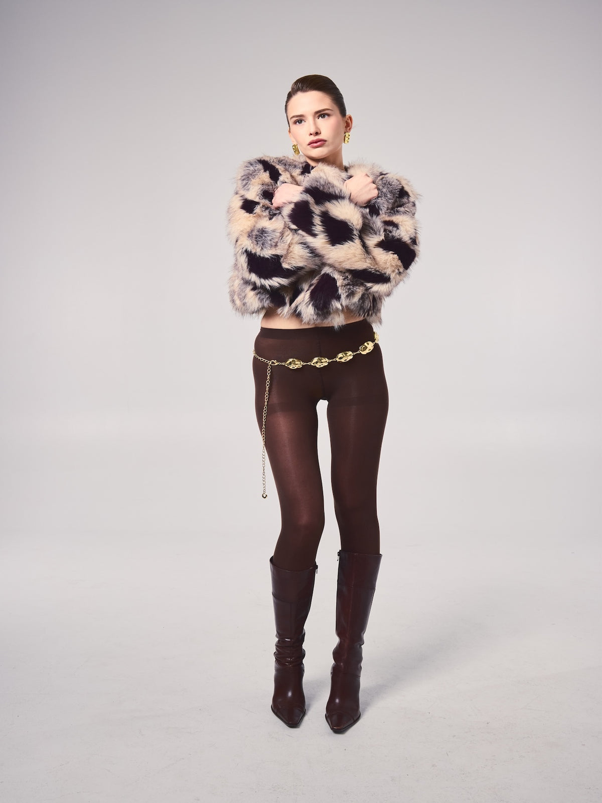 Model wrapped in a cropped vegan faux fur jacket showcasing its plush multi-tone texture and statement silhouette.
