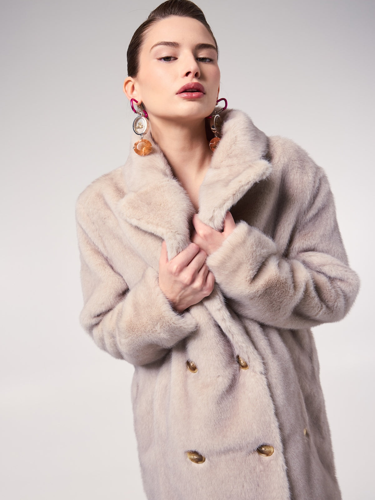 LONDON coat in Arctic Wolf — model wearing a double-breasted vegan faux fur coat with a soft Arctic Wolf finish, styled with statement earrings for an elegant cold-weather editorial look.